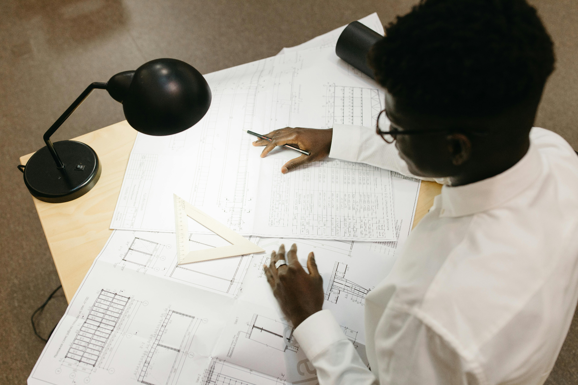 Quantity surveyor manually reviewing construction blueprints and drawings at a desk
